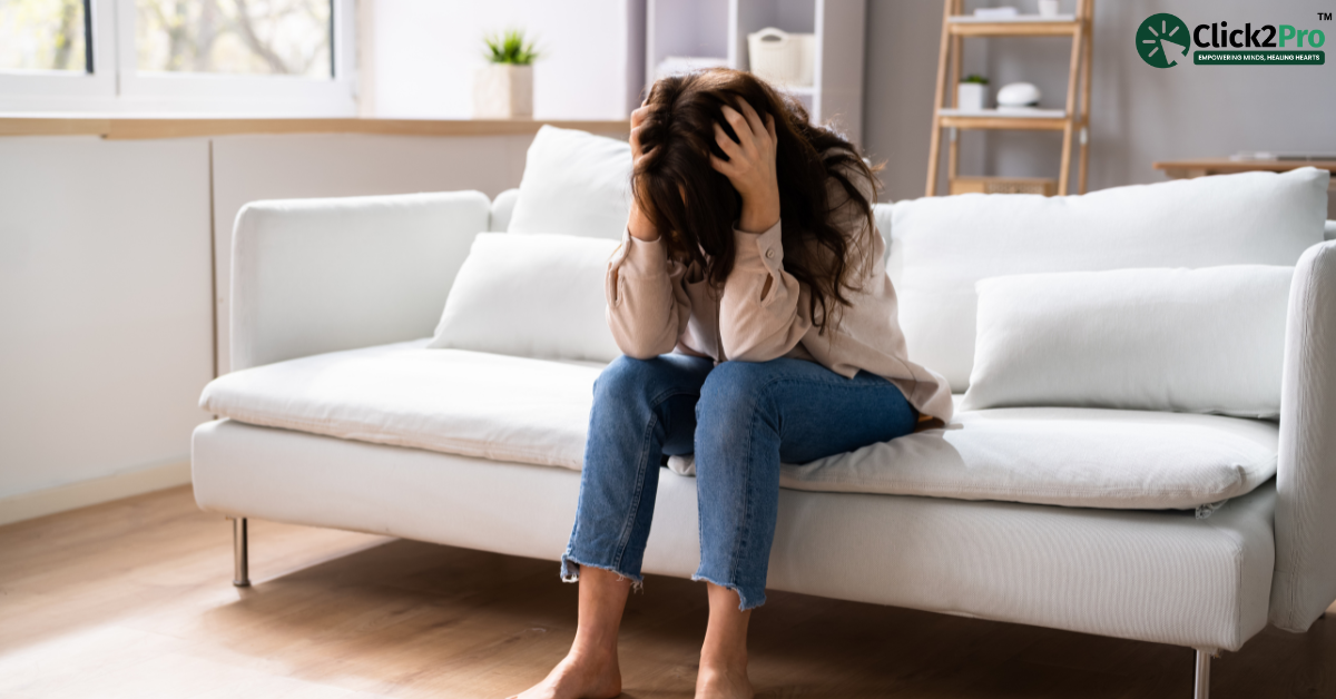 Person with somatic symptom disorder feeling distressed, sitting on couch, holding head in hands