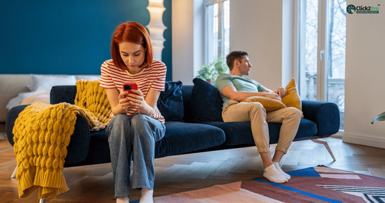 A couple sitting on a couch, both looking distant, illustrating symptoms of ROCD (Relationship OCD).