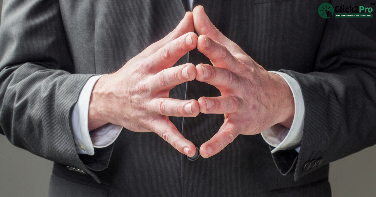 Man with steepled hands in suit, displaying assertive body language, highlighting nonverbal cues.