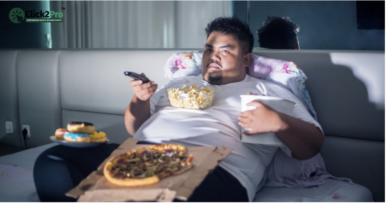 Man binge eating pizza and snacks while watching TV, illustrating binge eating disorder triggers.